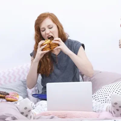 girl eating burger with people giving her multiple thumbs down