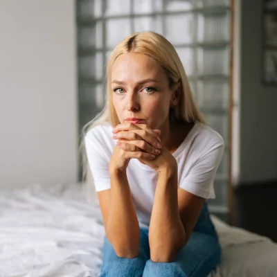 A young blonde woman resting her head on her clasped hands thinking about how she's feeling unappreciated.