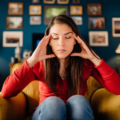Woman on couch with her head in her hands and eyes closed struggling with high functioning anxiety.